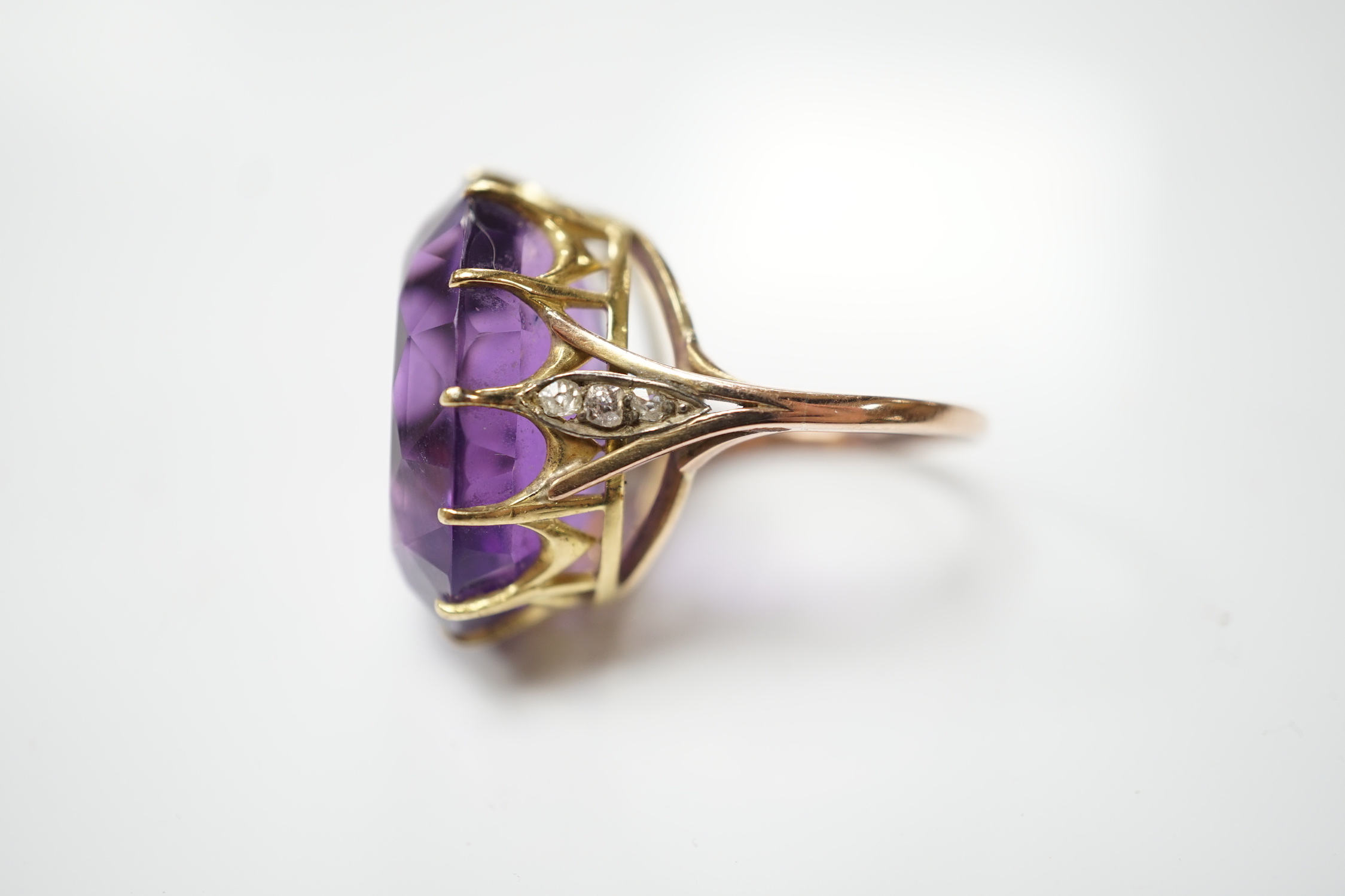 A yellow metal and oval cut amethyst set dress ring, with diamond chip set shoulders, size O, gross weight 10.6 grams.